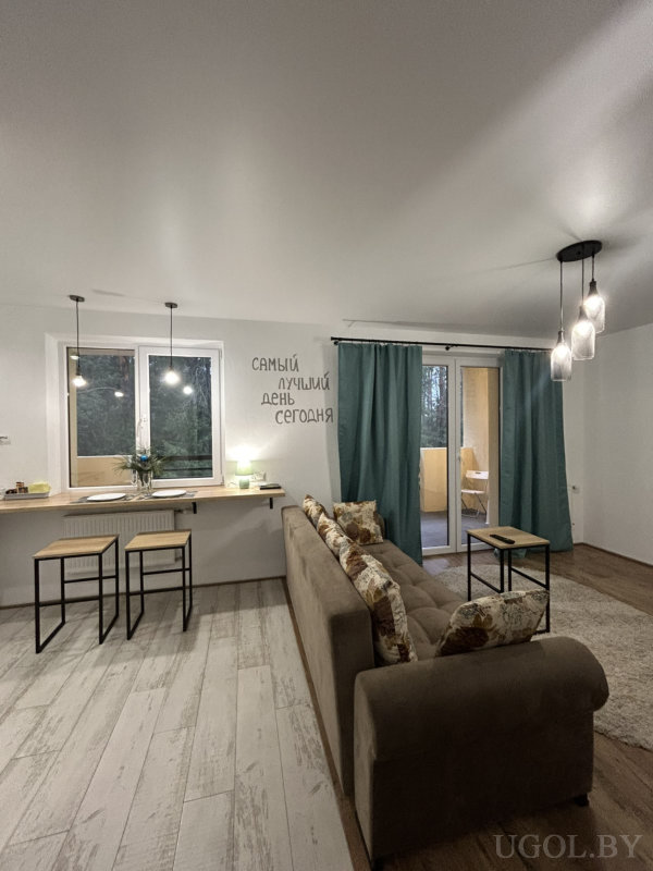 Комната с коричневым диваном, барной стойкой на двоих, подвесными светильниками и надписью «САМЫЙ ЛУЧШИЙ ДЕНЬ СЕГОДНЯ» между окнами.