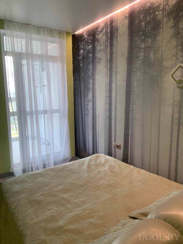 Уютная комната с текстильным покрывалом и настенной фреской леса, дополненной светодиодной подсветкой.