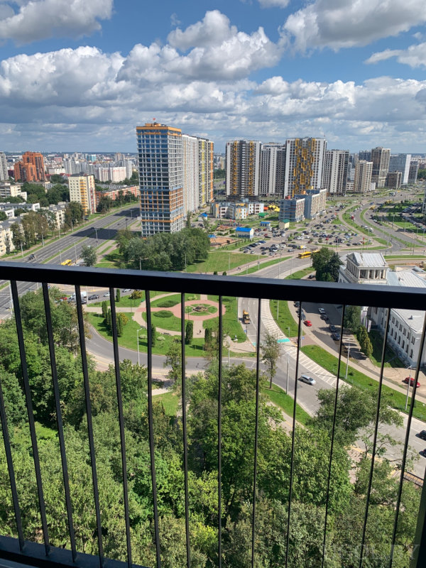 Вид на круговую развязку, жилые комплексы с цветными акцентами и элементы городской инфраструктуры.