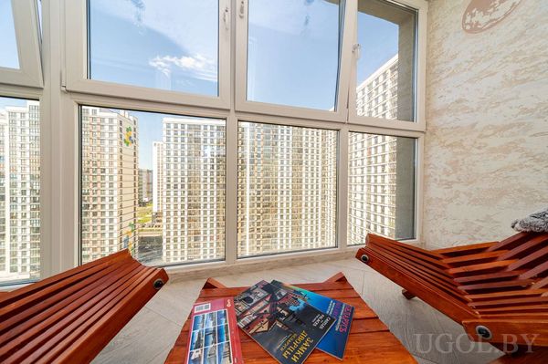 Зона отдыха с креслами, журнальным столиком и видом на город, на столе — журнал «ГЕНПЛАН МИНСКА».