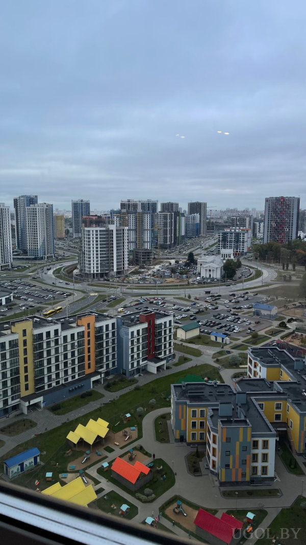 Высотная застройка, яркие детские площадки во дворе и классическое белое здание в центре кольцевого движения.