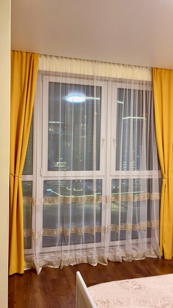 Композиция с тюлем, декоративным кантом, ночным освещением и фрагментом кровати на переднем плане.