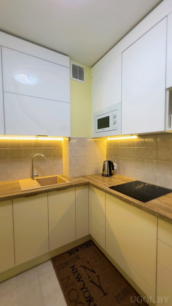 Угловая зона с плитой, чайником, глянцевыми фасадами, подсветкой и текстильным ковриком.