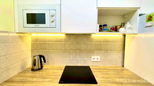 Композиция с микроволновкой, чайником, специями, календарём и плиточным фоном.