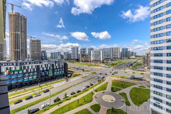 Панорамный городской пейзаж с современными высотками, многоуровневой дорогой, круговой площадью и зелёными зонами.