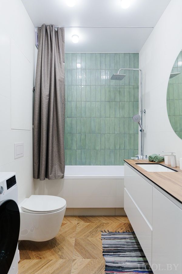 Компактная ванная с ванной, зелёной плиткой, стиральной машиной, унитазом и белой тумбой с зеркалом.