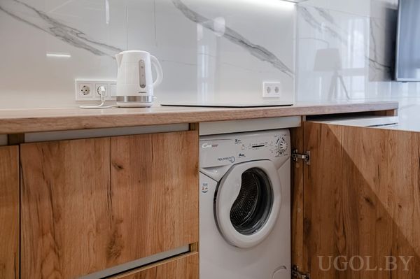 Современная кухня с деревянными шкафами, мраморным фартуком и встроенной стиральной машиной Candy.