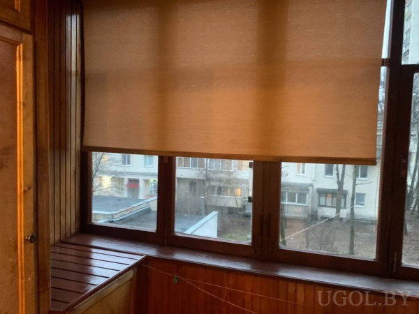 Застеклённая зона с жалюзи, деревянной отделкой, верёвкой и видом на жилой дом.