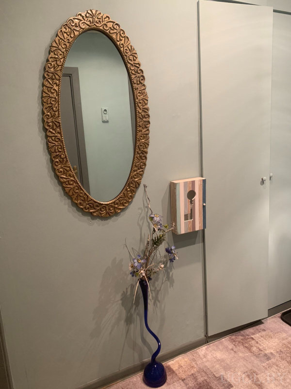 Композиция с зеркалом, вазой с цветами, декоративным ящиком и светлым ковром.