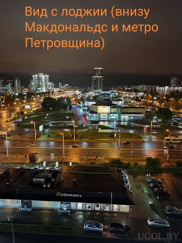 Городской ночной пейзаж с видом на Макдоналдс, метро Петровщина, улицу с машинами и освещёнными зданиями.