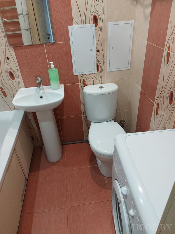 Комната с раковиной, унитазом, ванной с деревянной панелью и плиткой с овальными узорами.