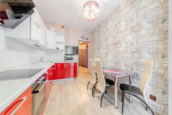 Комната с плитой, микроволновкой, столом с высокими стульями и обоями с архитектурным рисунком.