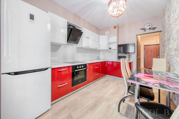 Интерьер с плитой, холодильником, столом с цветочным рисунком, телевизором и часами с силуэтами птиц.