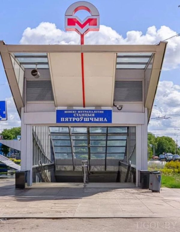 Городская сцена с входом в метро, стеклянной крышей, табличкой и лестницей вниз.