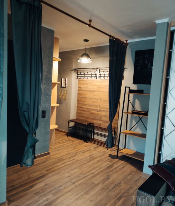 Интерьер с нишей, деревянной стеной, скамьей, шторой на потолочном карнизе и подвесным светильником.