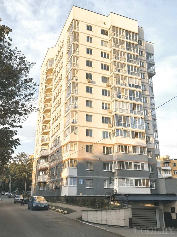Городской дом с серо-бежевым фасадом, балконами, номером «8» на стене и парковкой вдоль улицы.