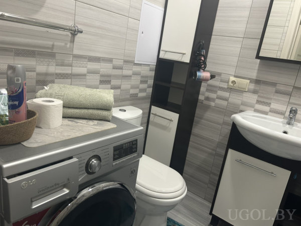 Стиральная машина LG, туалет, раковина и высокий шкаф, на машине — полотенца, корзина и бытовая химия.