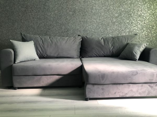 Мягкая зона с серым диваном, подушками, шезлонгом и фоном с текстурной отделкой в виде листьев.