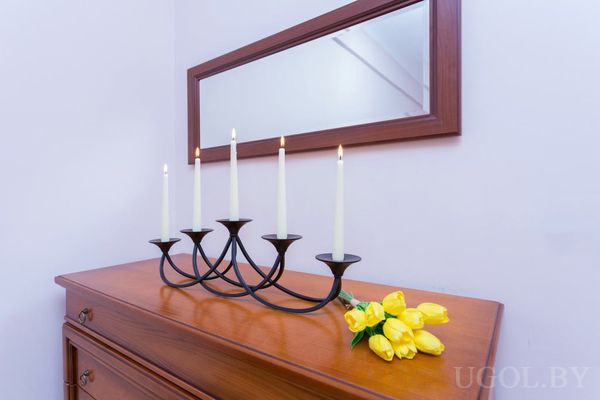 Деревянный комод с зеркалом, подсвечником на пять свечей и букетом жёлтых тюльпанов.