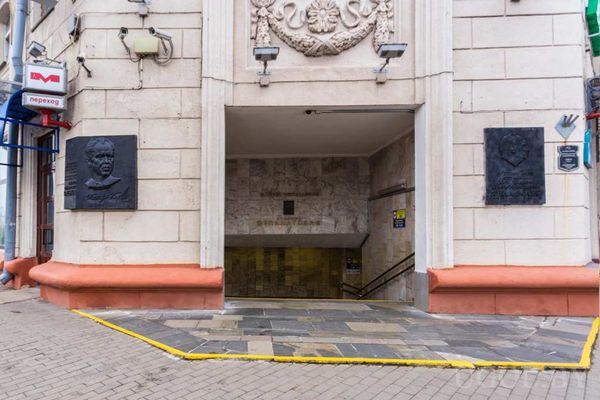 Каменное здание с входом в метро, гербом над дверью и памятными табличками по бокам.