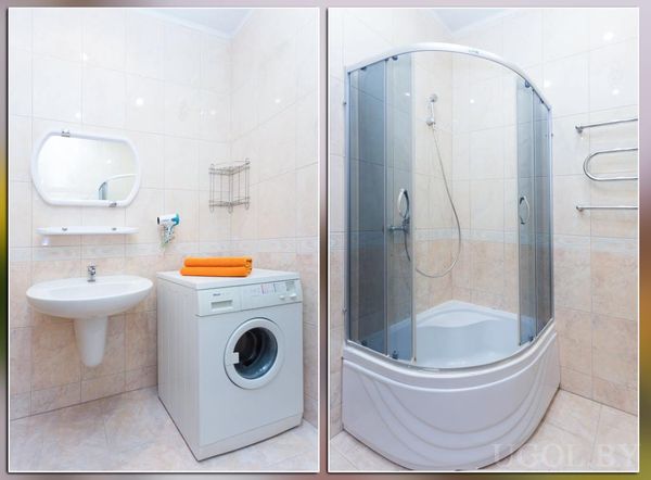 Современная ванная с душевой кабиной, стиральной машиной с оранжевыми полотенцами и настенным полотенцесушителем.