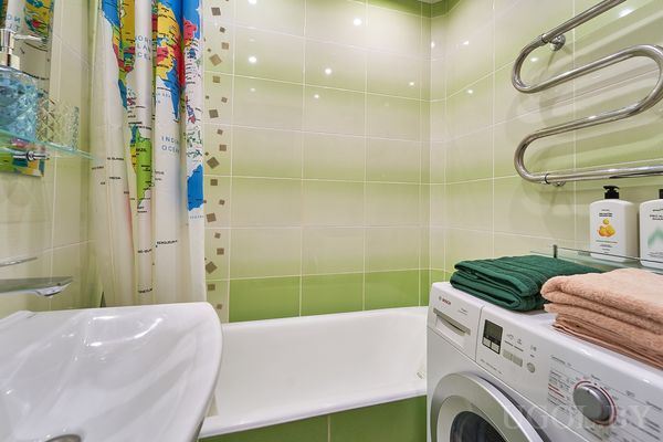 Компактная ванная с белой сантехникой, стиральной машиной и занавеской с картой мира.