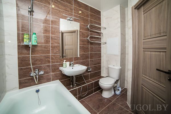 Ванная с белой ванной, раковиной, унитазом, зеркалом и коричнево‑белой плиткой.