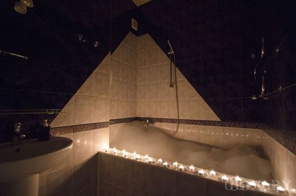 Ванна с пеной, множество свечей по периметру, плитка с треугольным узором, душ и раковина — атмосфера уюта и релакса.