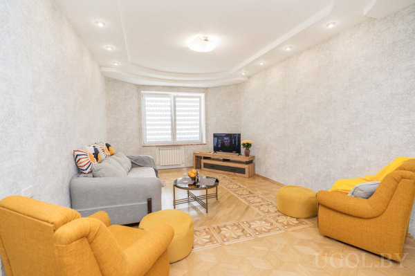 Серый диван, стеклянный стол, декоративная плитка на полу и светлая отделка стен.