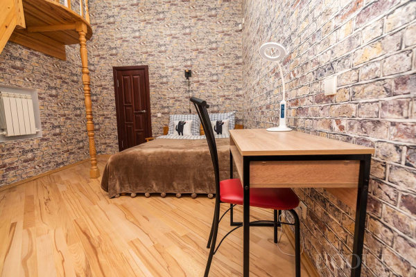 Коричневое покрывало, рабочий стол, деревянная лестница и уютная атмосфера лофта.