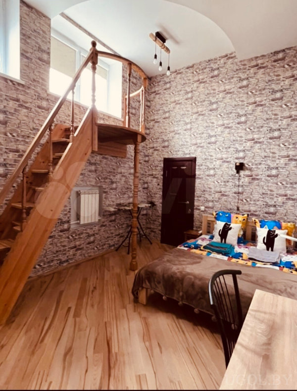 Кирпичная стена, деревянная мебель, декоративные элементы и высокий потолок.