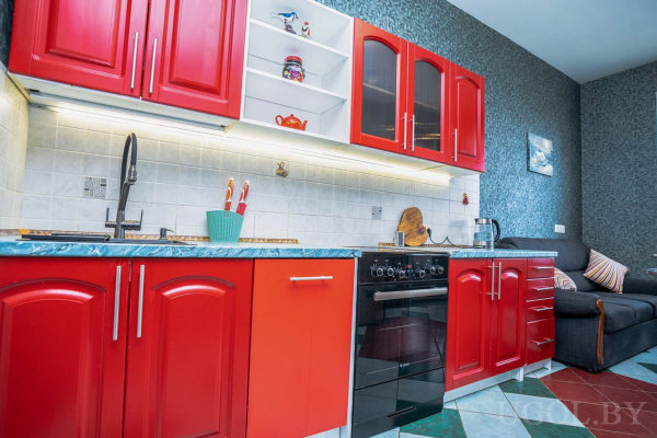 Красные шкафы, синий мраморный столешница, черная мойка и переход в гостиную.