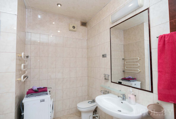 Бежевая плитка, зеркало с подсветкой, вертикальные полотенцесушители и аккуратный интерьер.