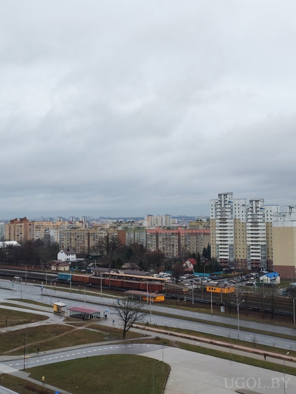 Вид на жилые дома, дорогу и железнодорожные пути с вагоном техобслуживания и остановкой.