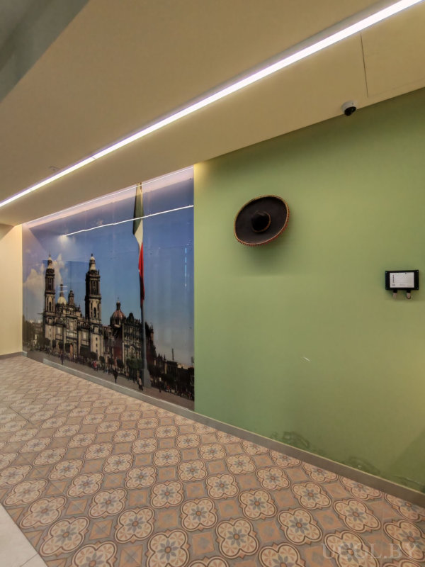 Стена с фреской собора и флагом Мексики, мексиканская шляпа и плитка с узором на полу.