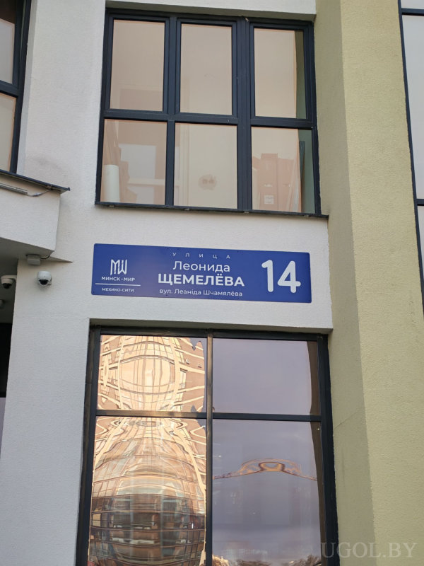 Указатель с надписью «Улица Леонида Щемелёва, 14» на фасаде современного здания.