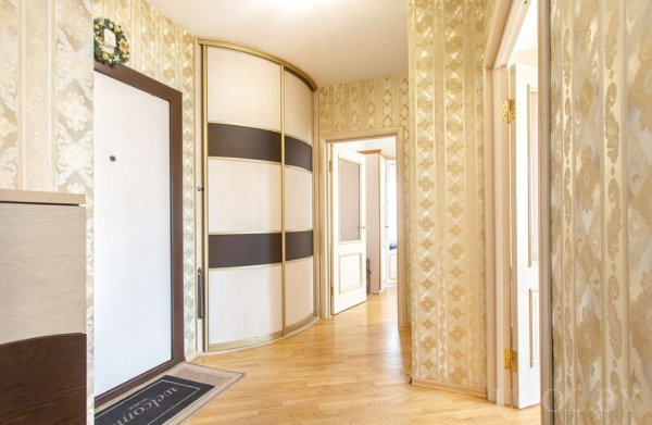 Элегантная прихожая с обоями «дамаск», светлым полом и шкафом с черными полосами.