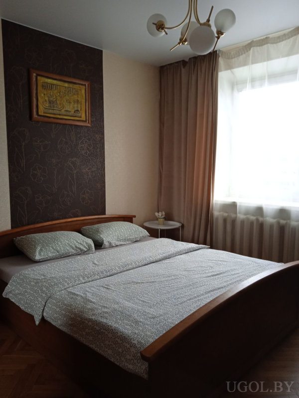 Комната с темной цветочной стеной, деревянной кроватью, светлым текстилем и мягким освещением.