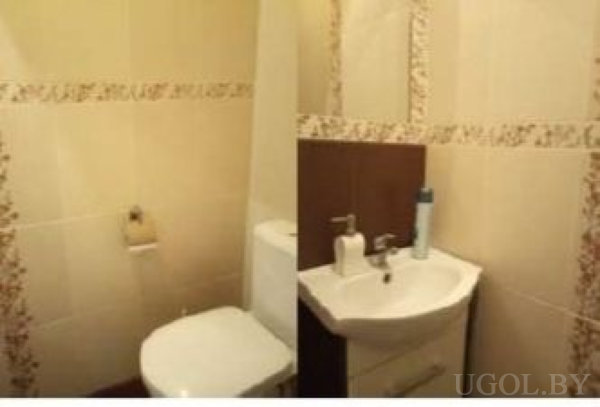 Туалет и раковина с аксессуарами, бежевые плитки с цветочным бордюром и симметричный эффект изображения.