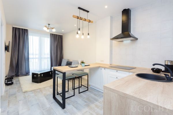 Интерьер с деревянной столешницей, белыми фасадами, чёрной техникой, барными стульями и подвесным светом.