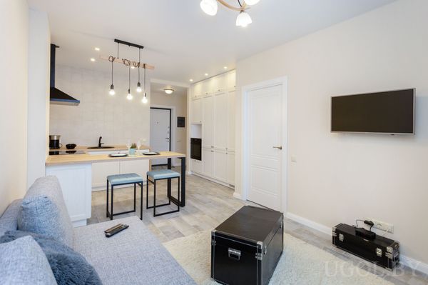 Комната с диваном, столом, телевизором, барными стульями, белыми фасадами и плиткой.