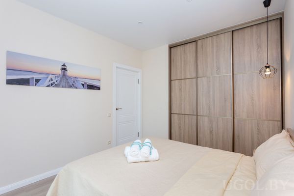 Интерьер с кроватью, полотенцами, фото на стене, дверью, шкафом и подвесным светильником.