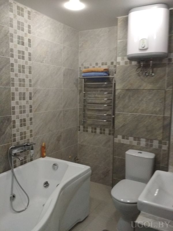 Интерьер с ванной, душем, умывальником, унитазом, полотенцесушителем и декоративной отделкой.