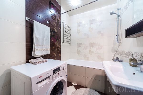 Комната с ванной, умывальником, стиральной машиной Bosch и плиткой с цветочным декором.