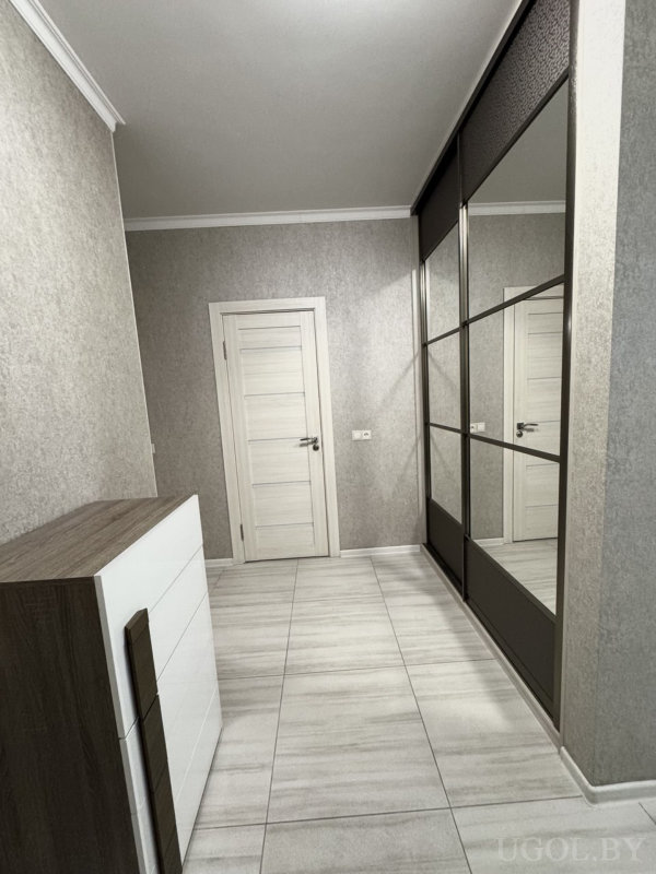 Интерьер с дверью, шкафом, комодом, плиткой, серыми обоями и потолочным светильником.