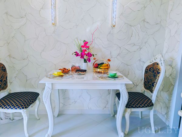 Сервировка на двоих с чашками, фруктами, цветами и фоном с вертикальными светильниками.