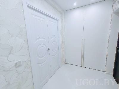 Интерьер с белыми дверями, шкафами, цветочными обоями и глянцевым полом на фоне светлого потолка.