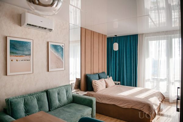 Спальня с двуспальной кроватью, зелёным диваном и панелями на стене