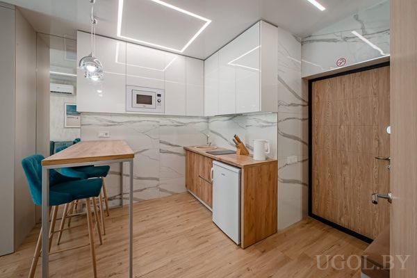 Кухня с белыми шкафами, деревянной столешницей и барными стульями