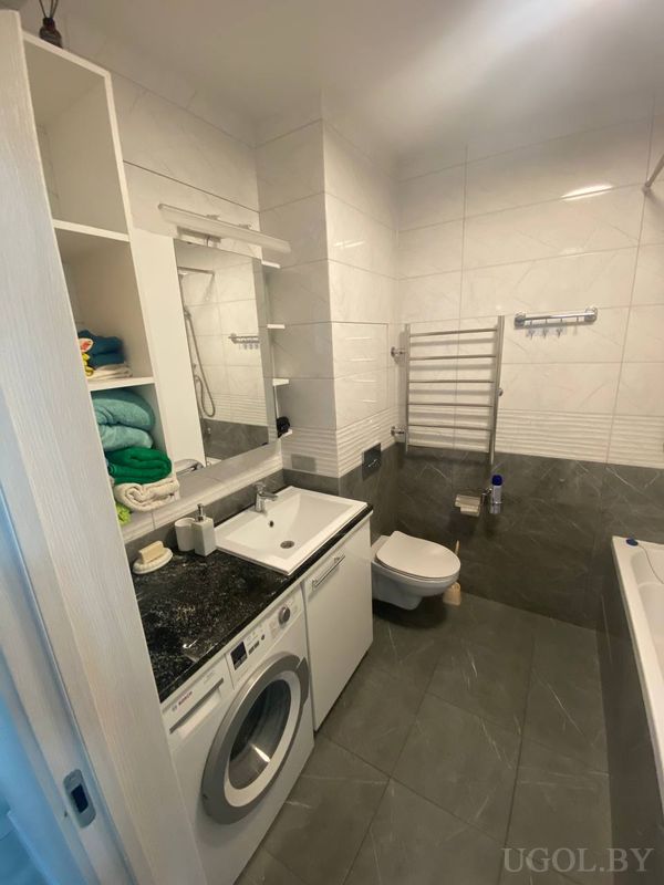 Комната с унитазом, умывальником, стиральной машиной и ванной, оформленная в бело-серой гамме.